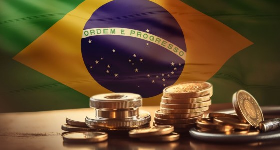 Moedas douradas à frente de bandeira do Brasil