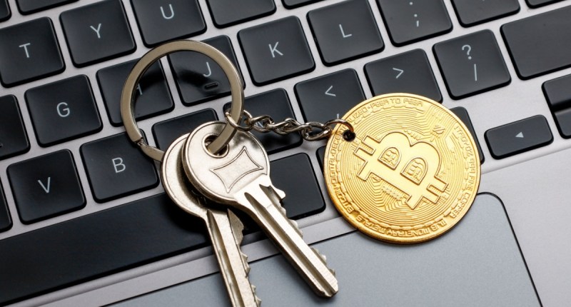 chaveiro com moeda de bitcoin em cima de teclado de laptop