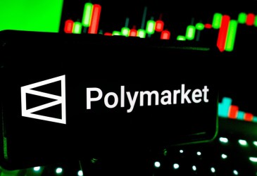 Smartphone mostra logo da plataforma de previsão Polymarjet; ao fundo, um gráfico de mercado financeiro